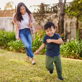 Mother chasing smiling boy on grass