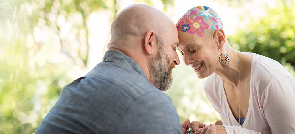 Cancer patient with head painted with her husband
