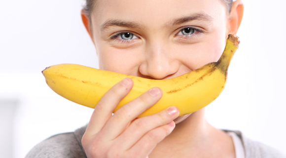 Child holding banana to face like a smile