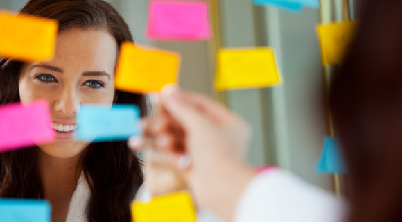 Woman smiling in mirror with sticky notes on it