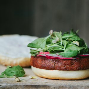 Burger topped with spinach and radishes