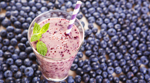 Blueberry smoothie surrounding by more blueberries