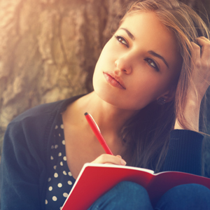 Young woman writing in journal in deep thought