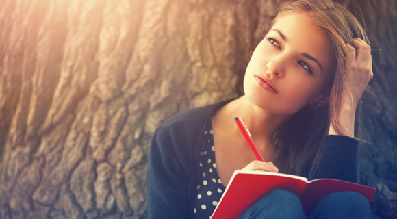 Young woman writing in journal in deep thought