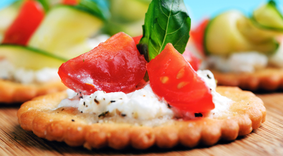Appetizer of tomato, cheese, and herbs on a cracker