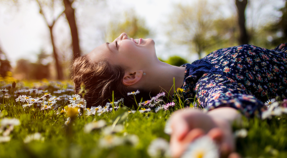 Woman lying down on top of grass smiling.