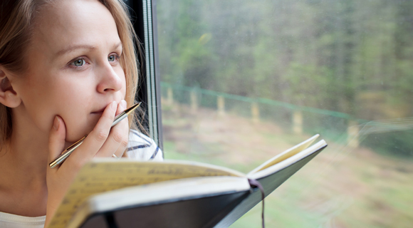 Woman with journal looking out window