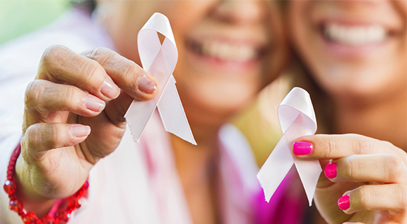 Two women holding up pink ribbons for breast cancer