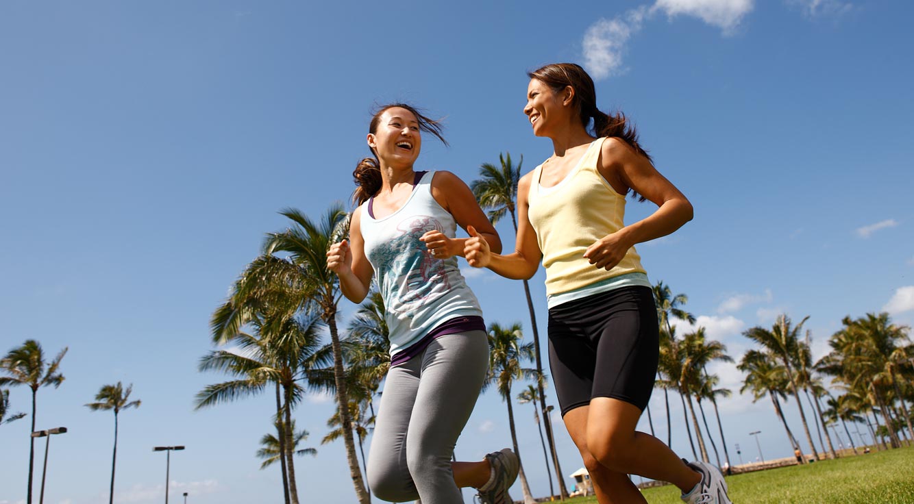 Two young women running through a Honolulu city park