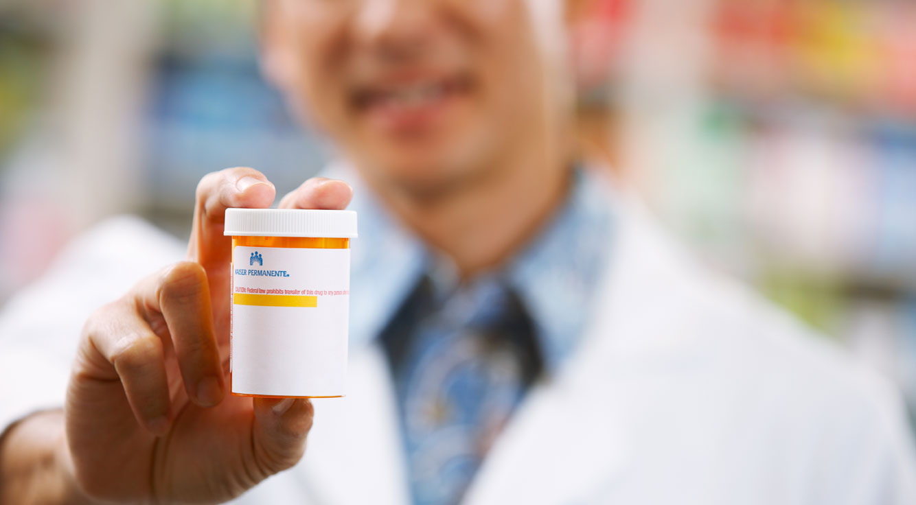 A pharmacist holds out a pill bottle.