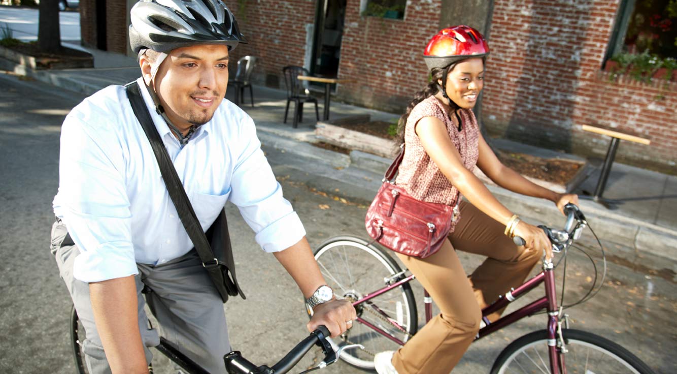 A man and a woman ride bicycles down a street.