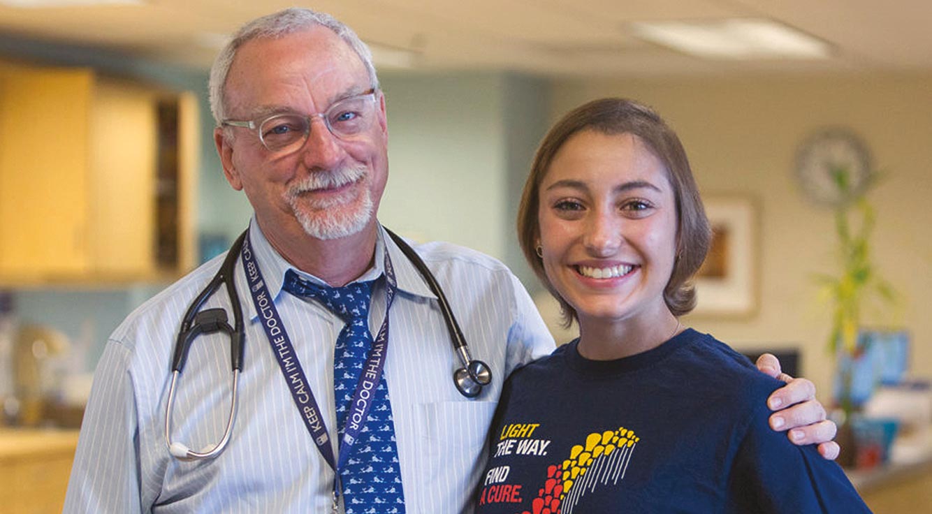 A thin young woman grins with her doctor.