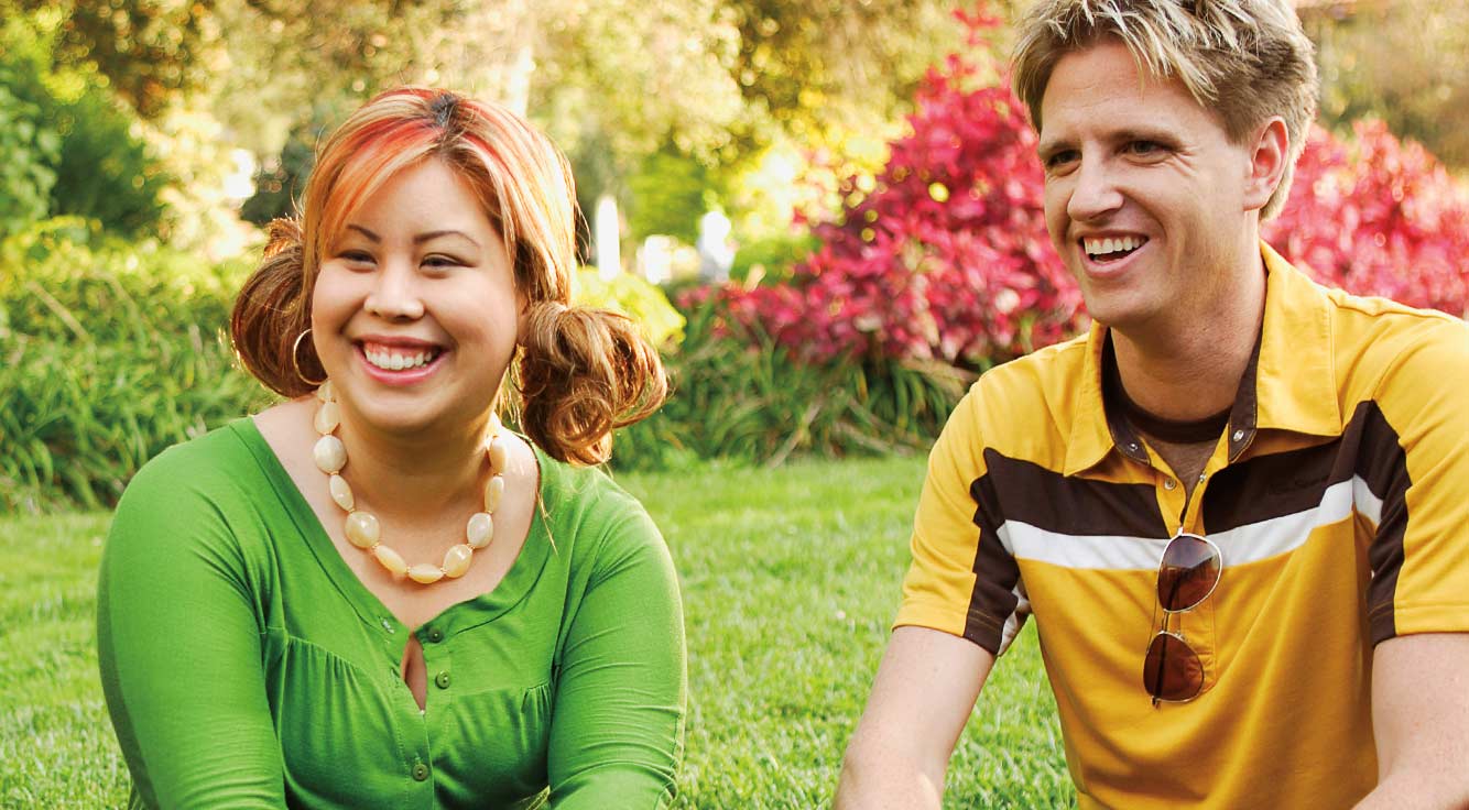 A young man and woman smile outdoors.