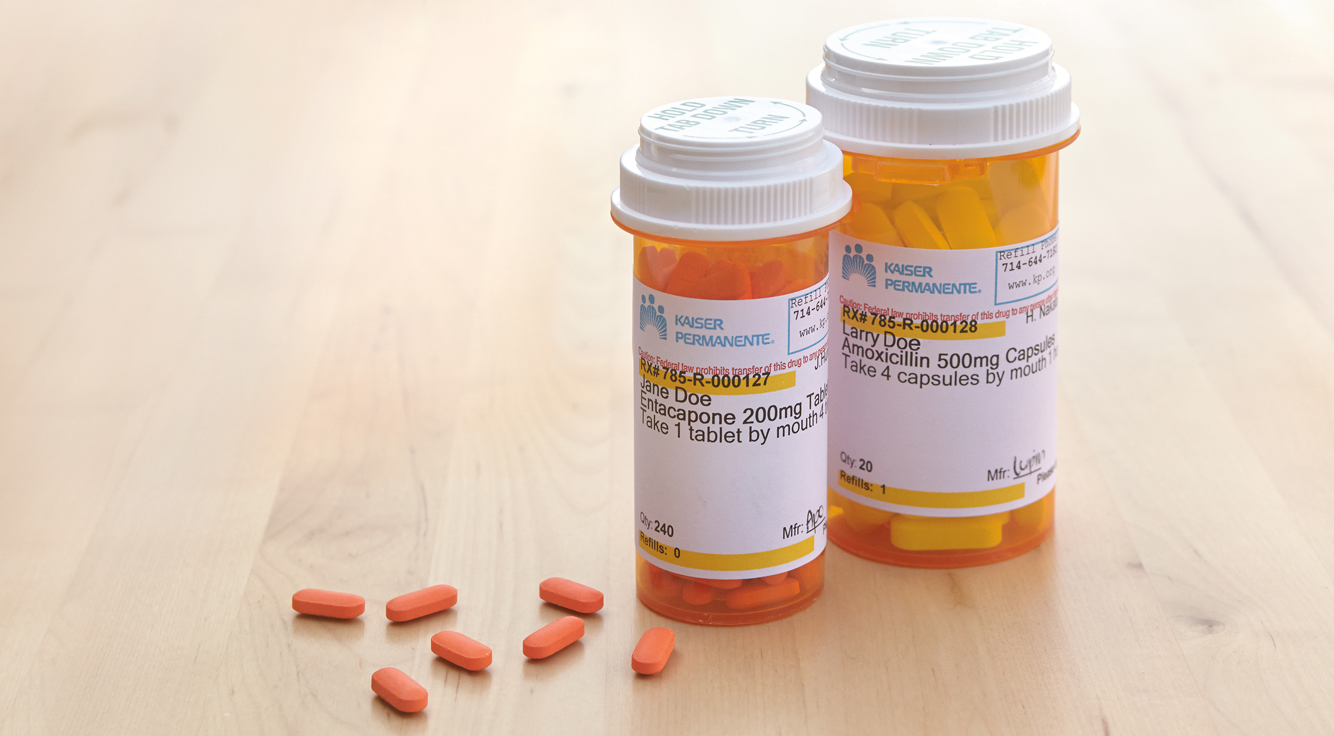 Pills rest on a surface near two prescription bottles