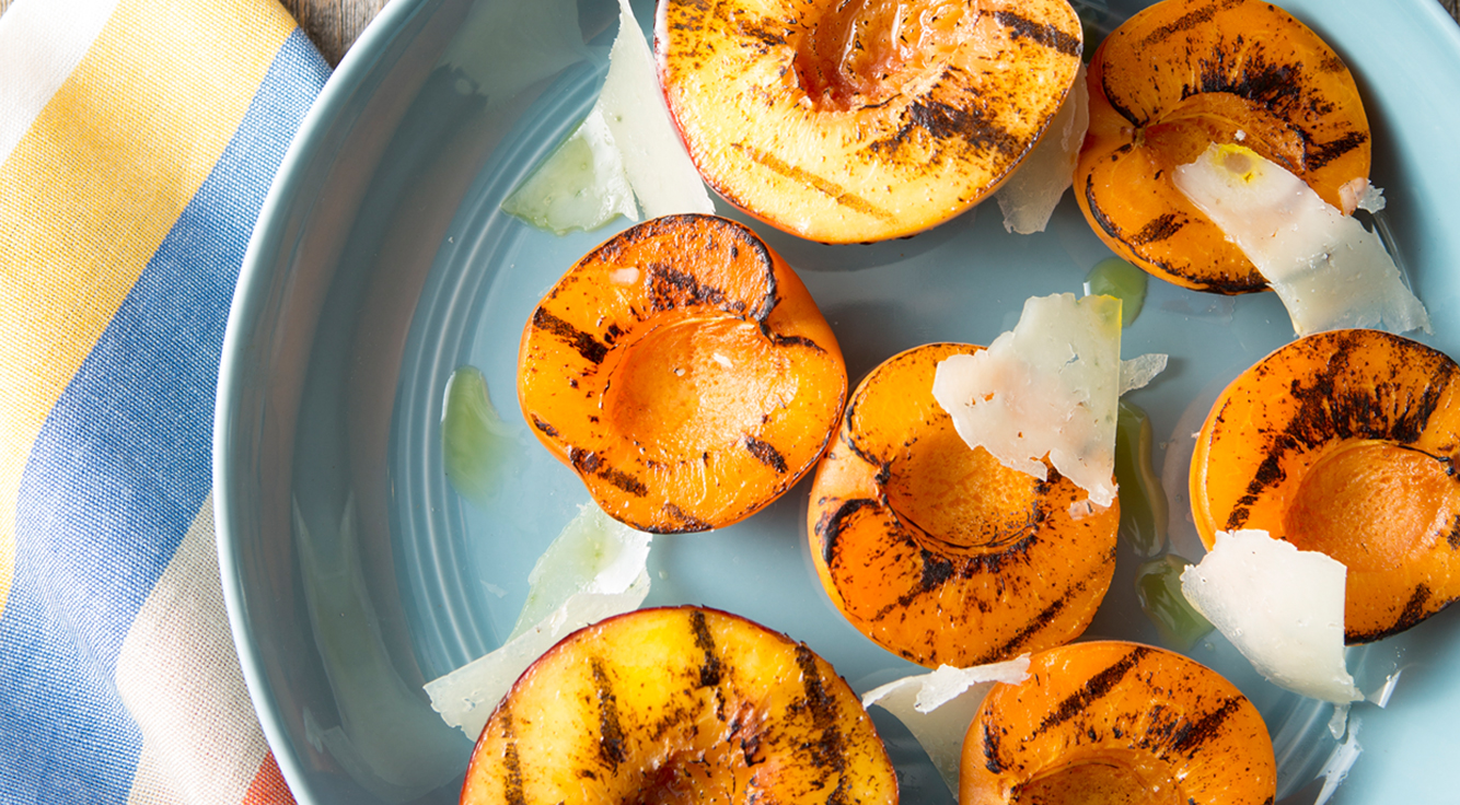 Grilled peaches rest on a plate.