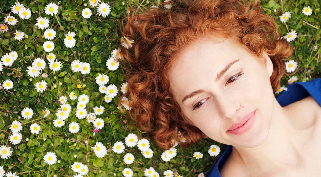 A woman lies in a field of flowers.