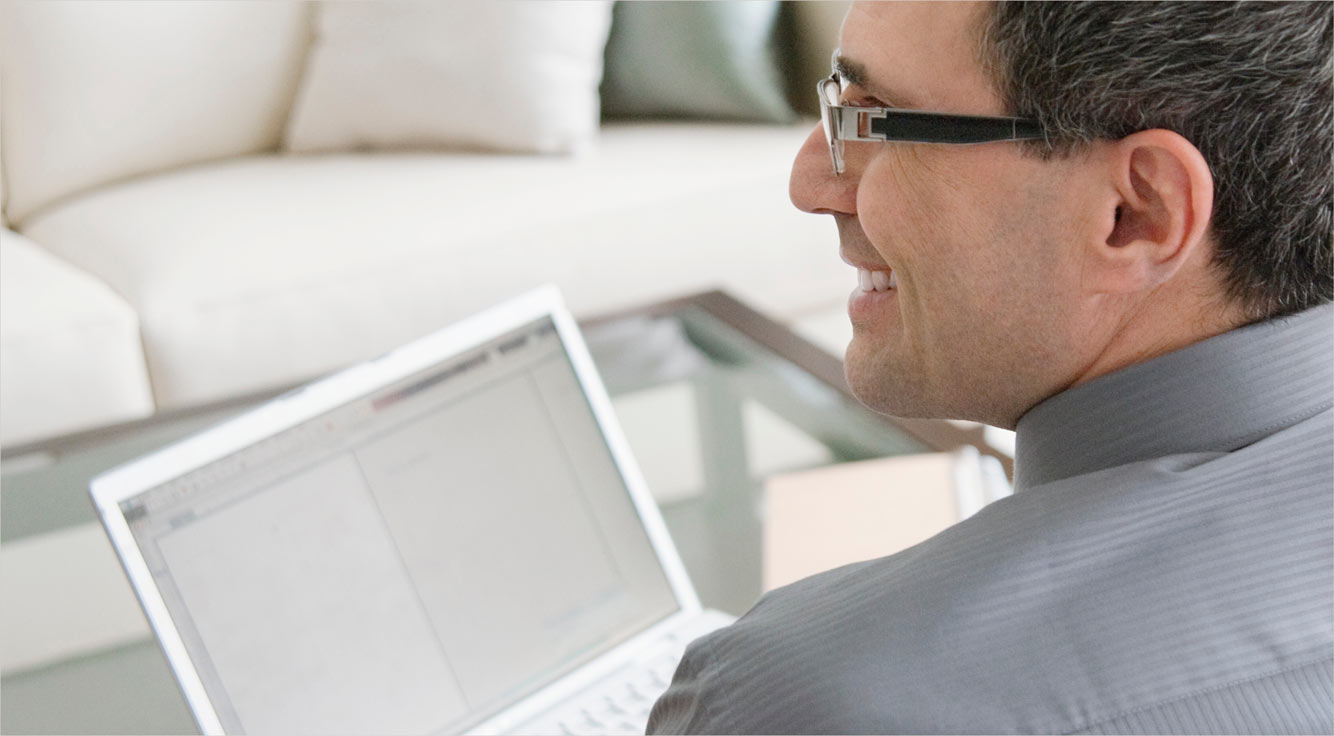 A man smiles at a laptop.