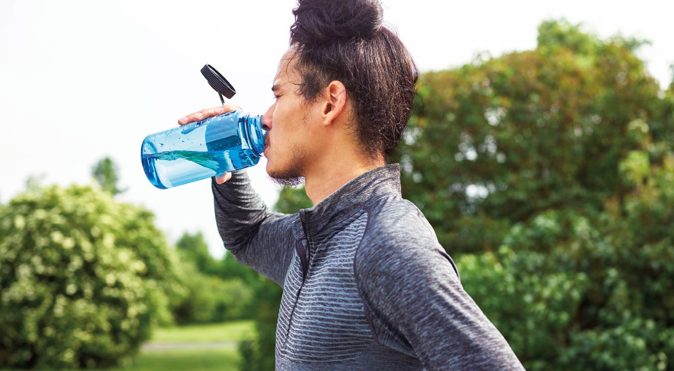 A man drinks water from a reusable bottle.