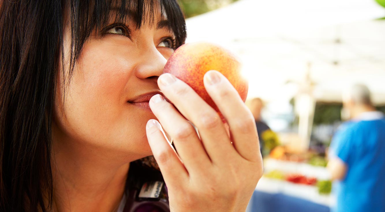 A young woman enjoys eating an apple outdoors.