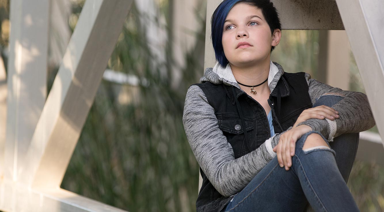 A teenager deep in thought sits in a park.