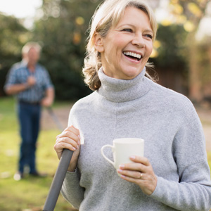 Smiling woman stands outside with a coffee mug