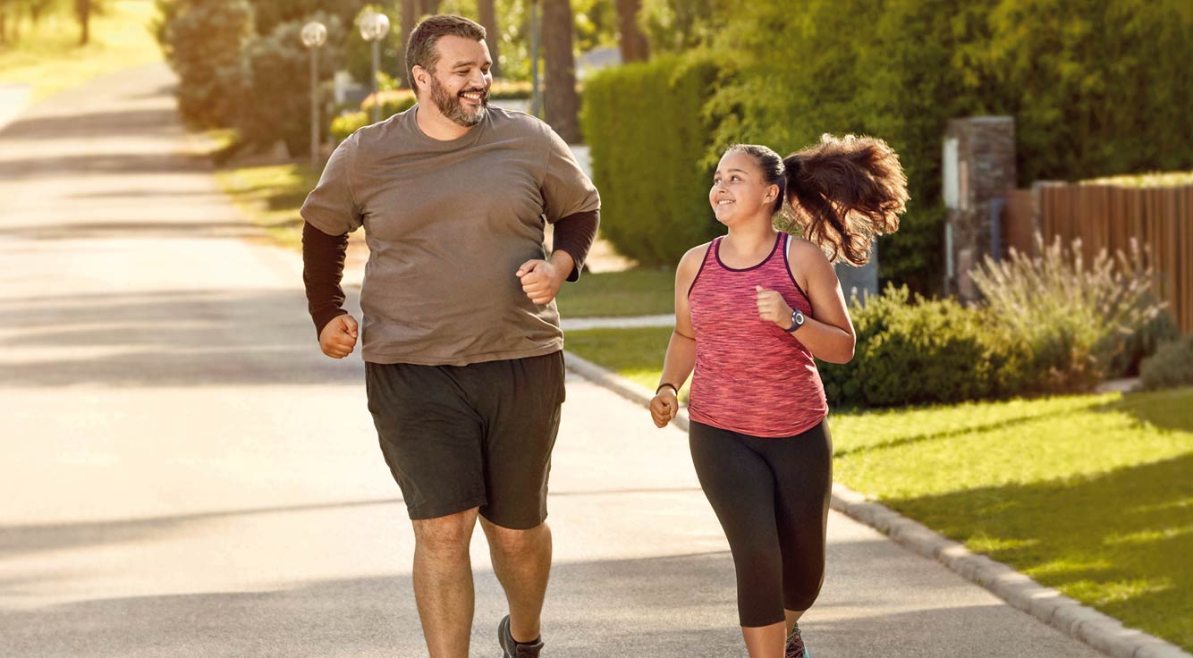 A man jogs with his daughter on a sunny day.