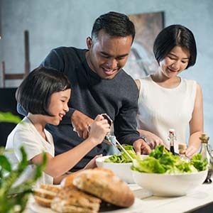 A smiling family makes salad together.