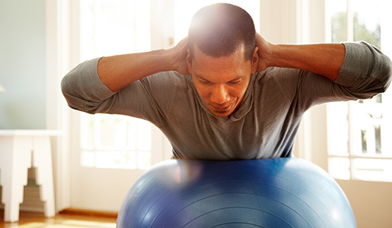 A man working out at home using a yoga ball