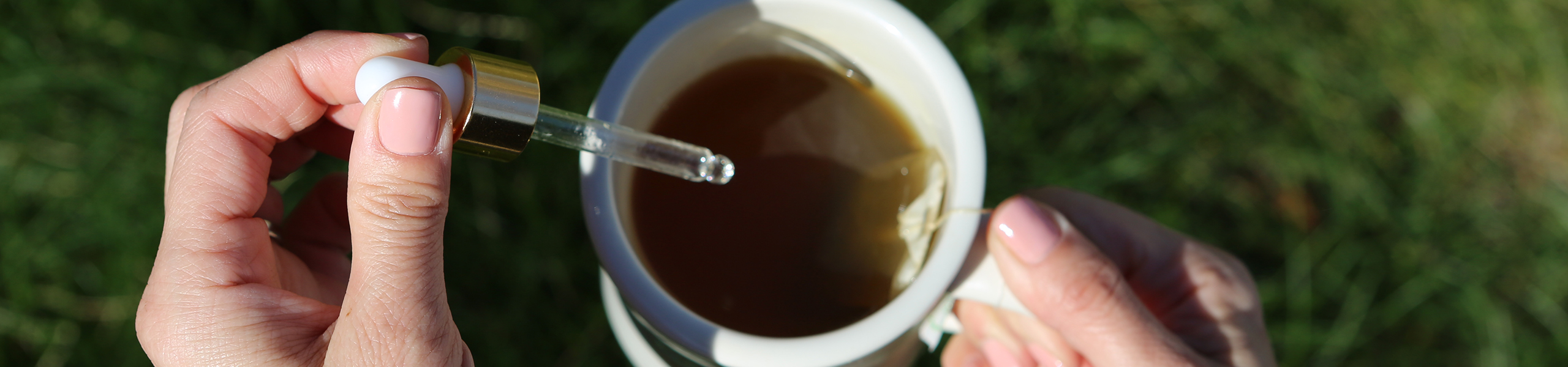 A person adds CBD oil to a cup of tea.