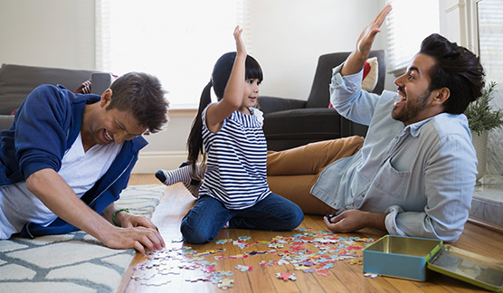 A family puts a puzzle together on the floor and shares a high five.