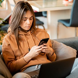 Young woman on couch holds smartphone in her hands