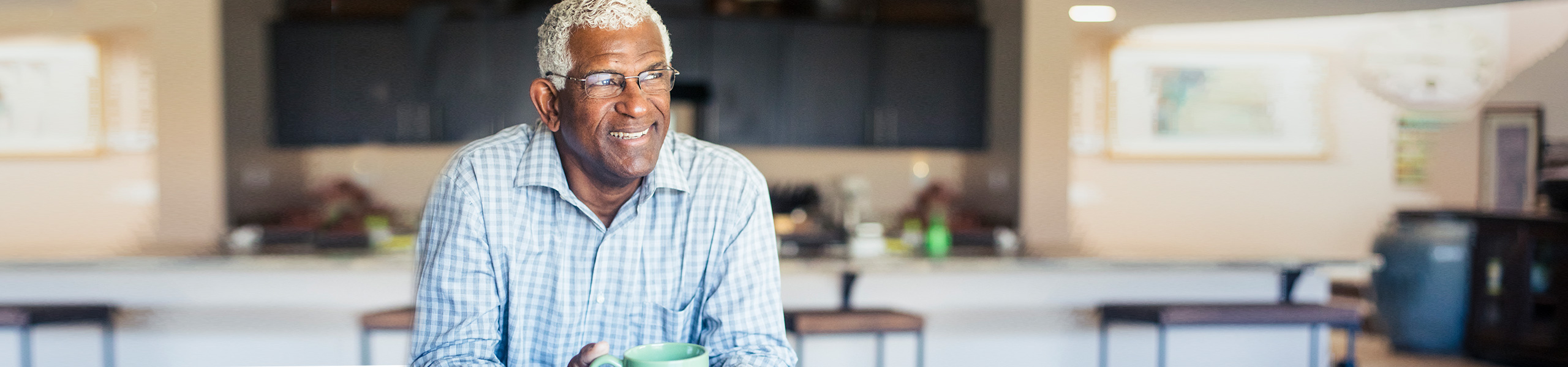 Smiling older man holds cup of coffee