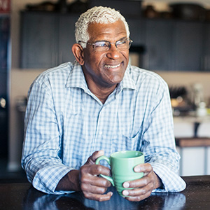 Smiling older man holds cup of coffee