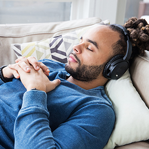 Young person wearing headphones rests on a couch