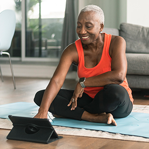 A happy older person sits on a yoga mat