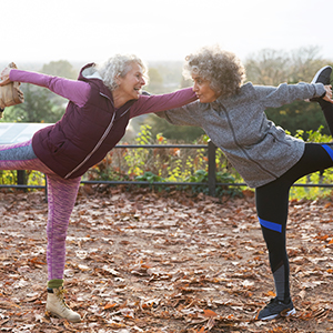 Smiling older women in workout clothes stretch outside