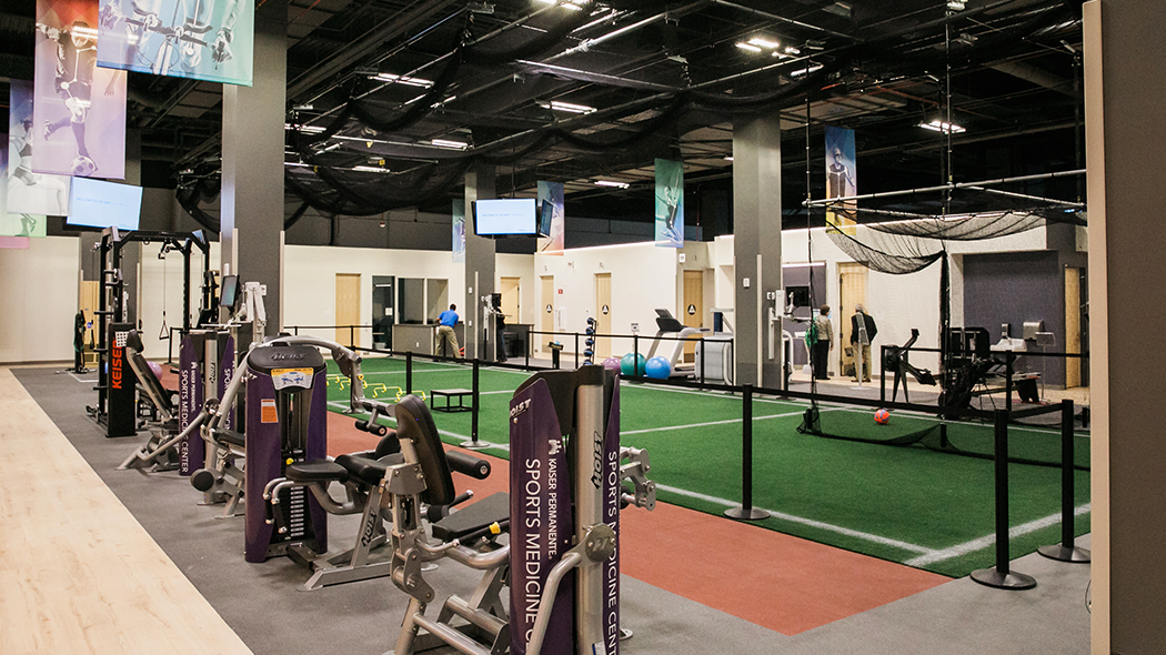 Rehabilitation space with 74-foot long sprint lane running through the center of the room and Kaiser Permanente branded exercise machines in the foreground