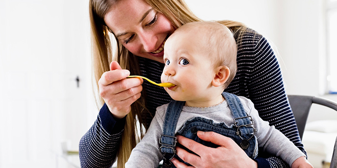 Mother spoon feeding young child.